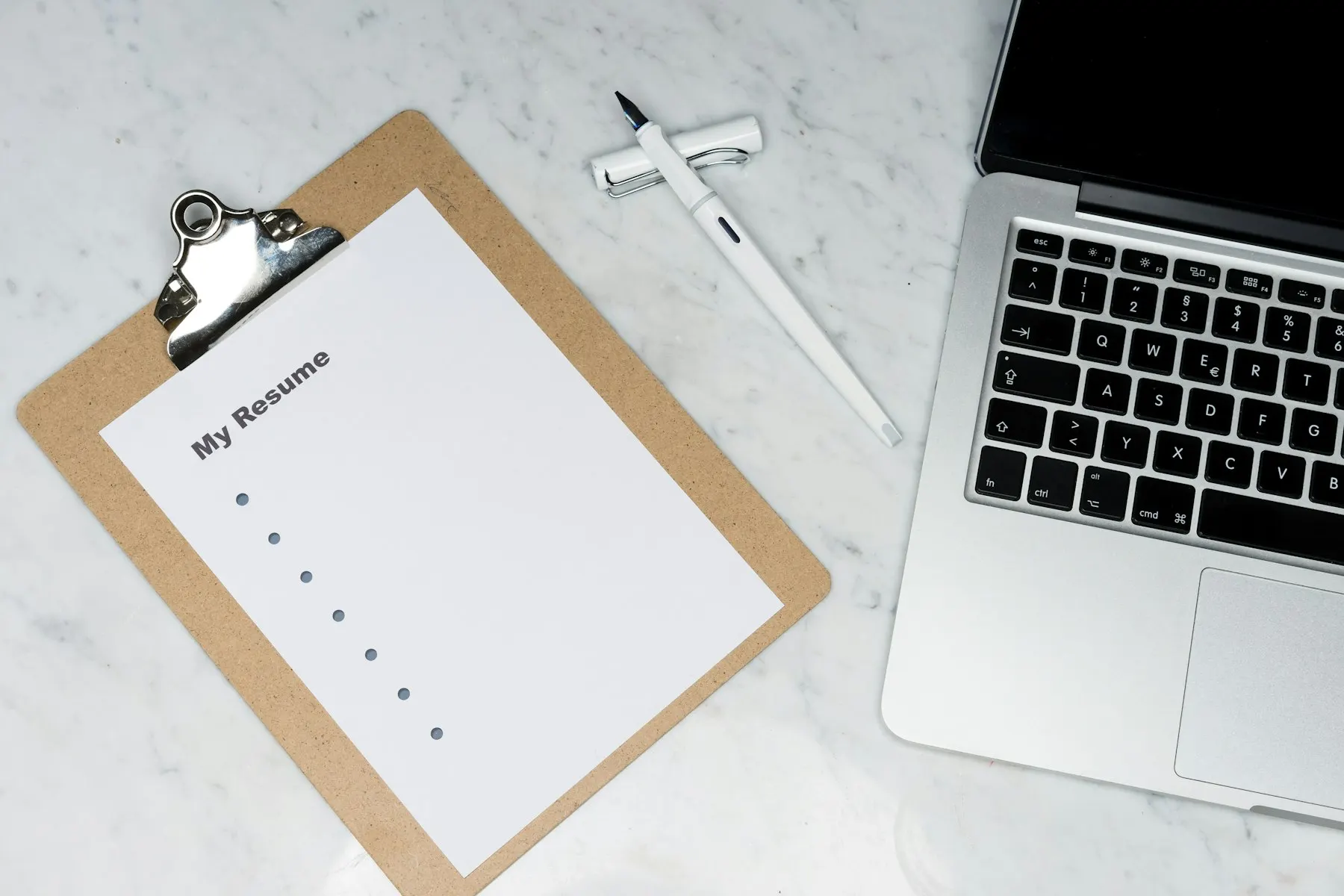 Clipboard with a blank resume page next to a laptop