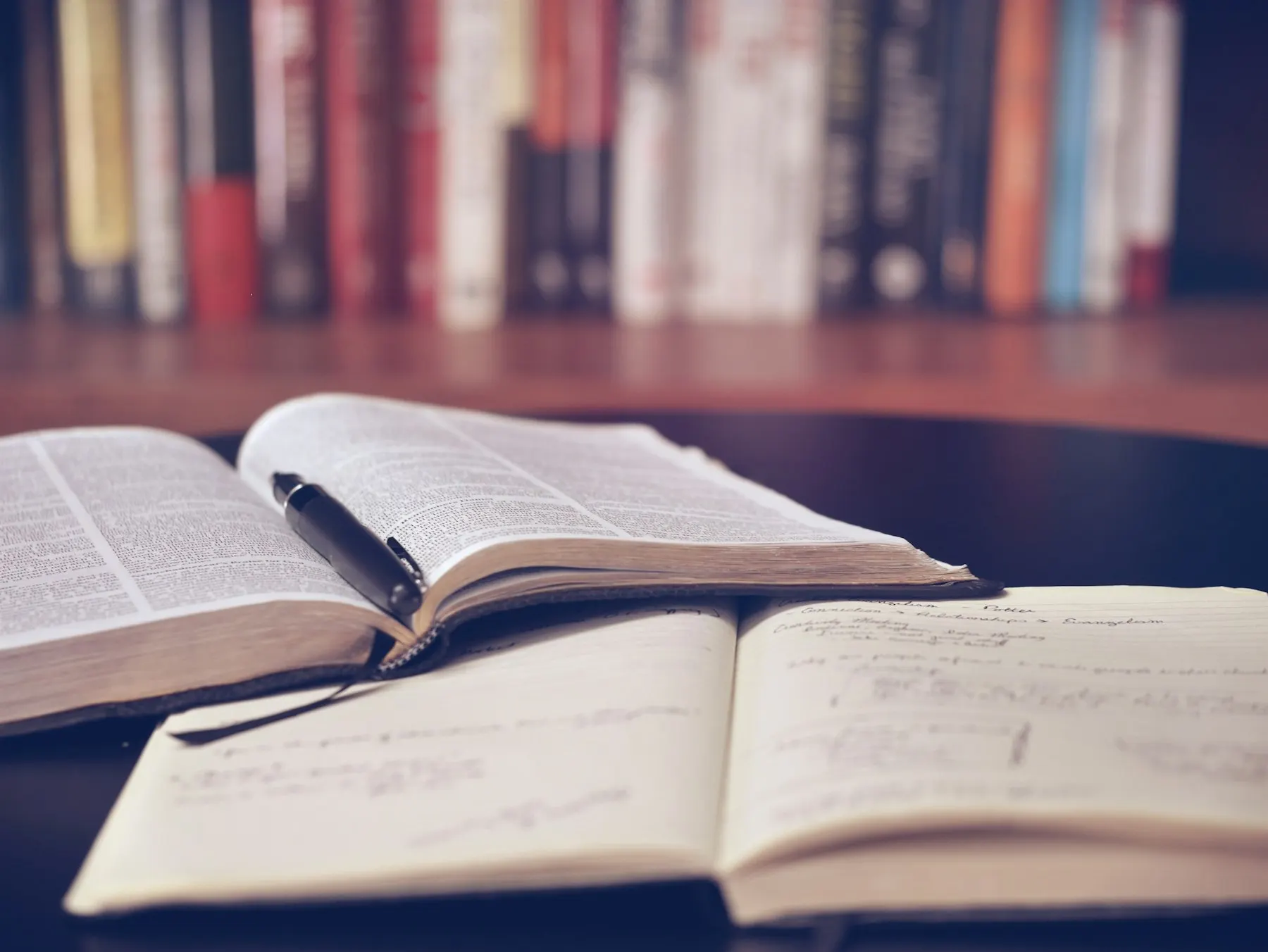 Open books with handwritten notes and a pen