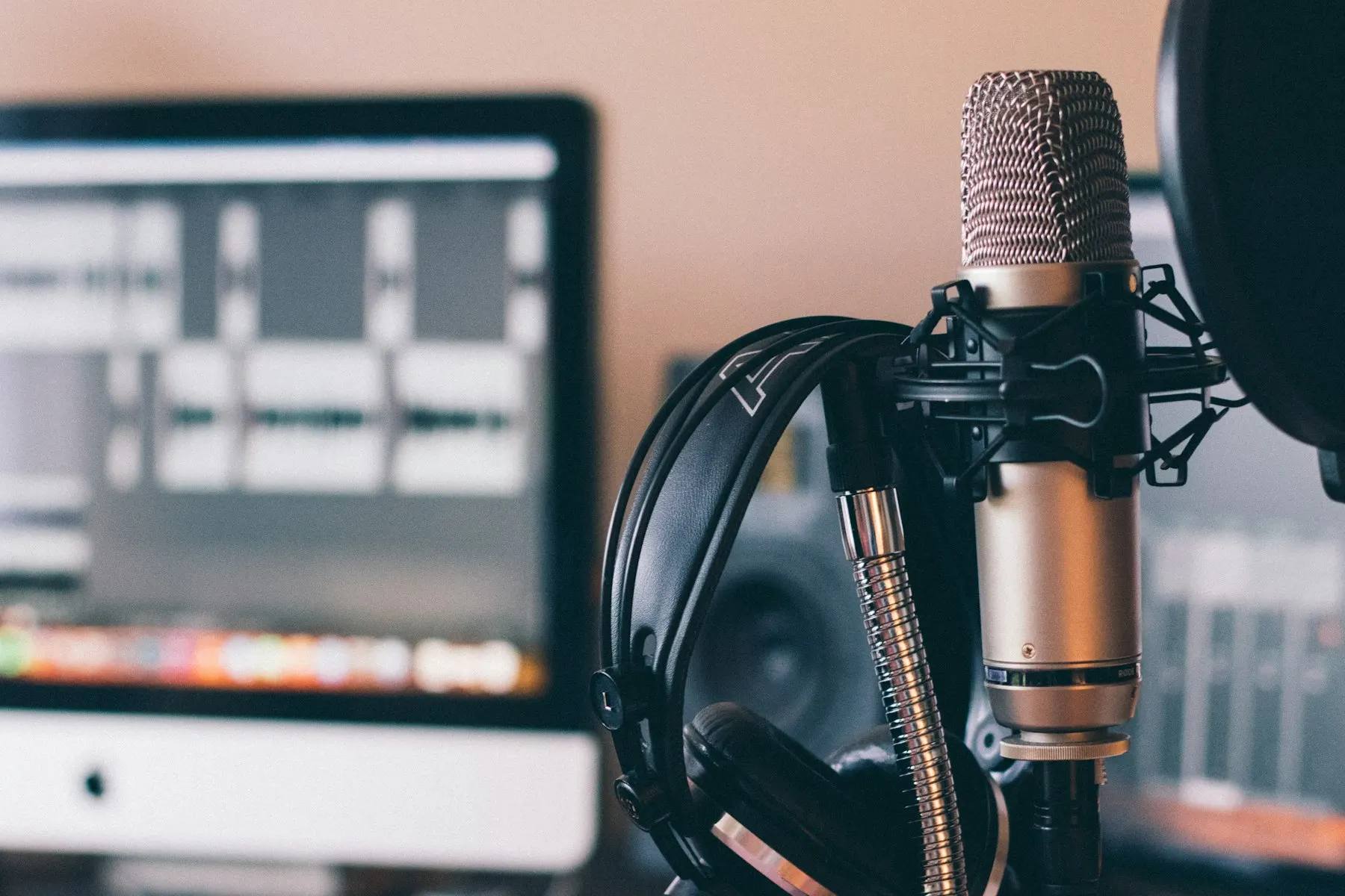 Studio microphone with headphones in front of a computer screen